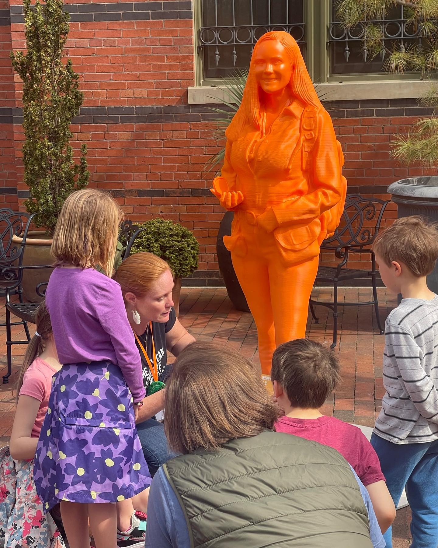 Wendy Bohon talking with children beside her orange IF/THEN statue.