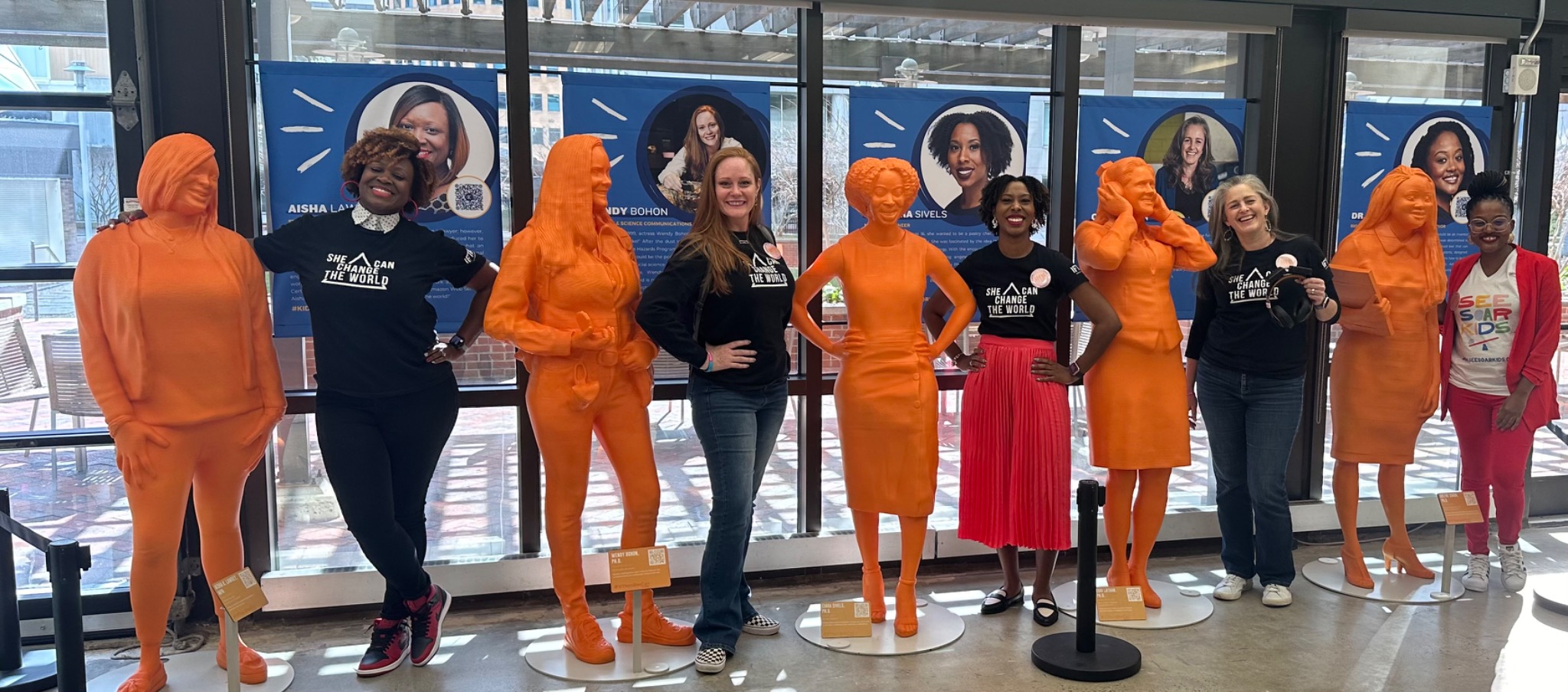 Wendy Bohon and fellow IF/THEN ambassadors standing beside their orange statues.